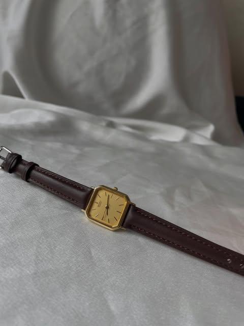 Seiko mặt champagne, dây da nâu trên nền vải trắng